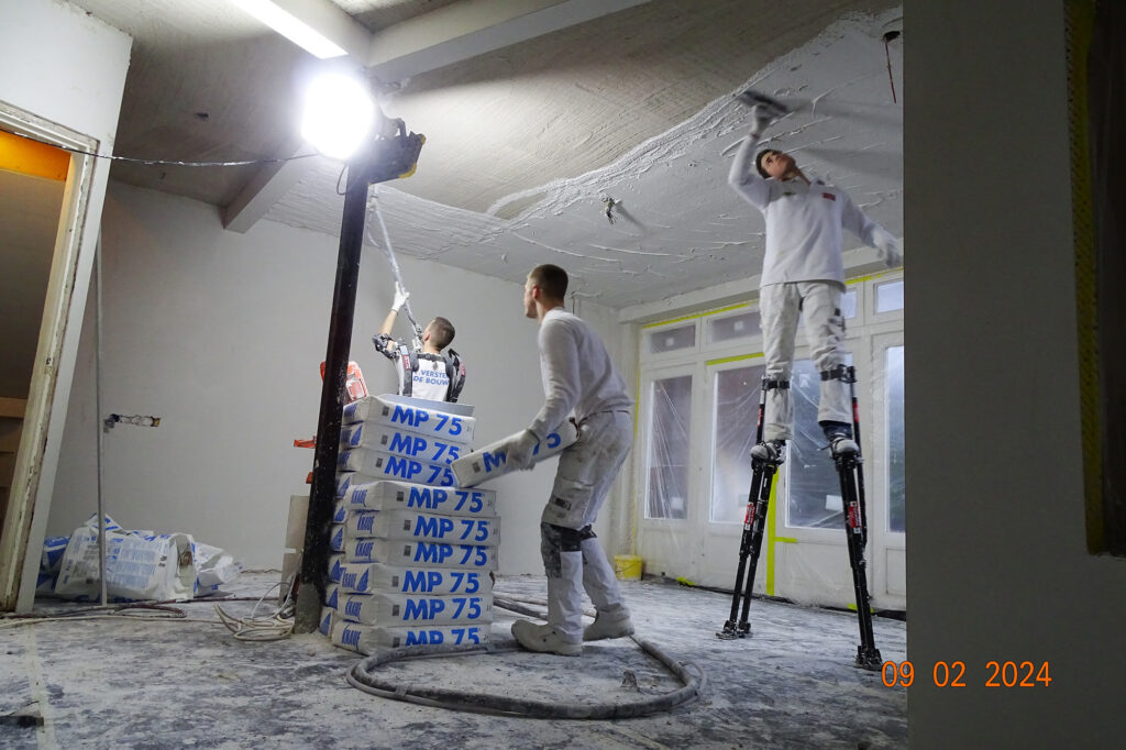 Het aanbrengen van pleisterwerk op het plafond met behulp van stukadoorsstelten.